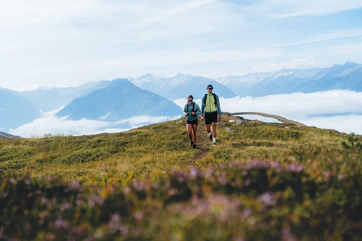 Sportovní rodina na túře v oblasti vysokohorské turistiky Wildkogel za jasného letního dne – rodiče a děti si společně užívají přírodu a aktivní rodinný čas v horách s výhledem na Alpy.