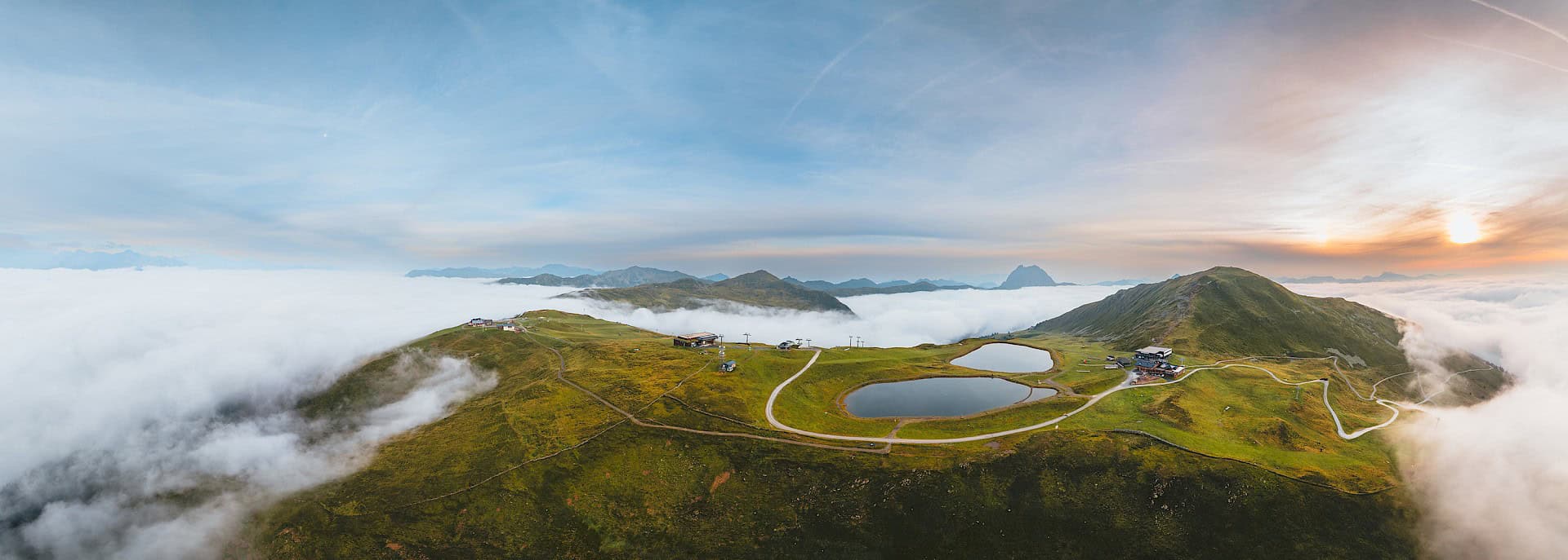 Sonnenaufgang über der Wildkogel-Arena mit Blick auf grüne Almwiesen, Wanderwegen und Wolkenmeer – unvergessliche Aussicht im Nationalpark Hohe Tauern.