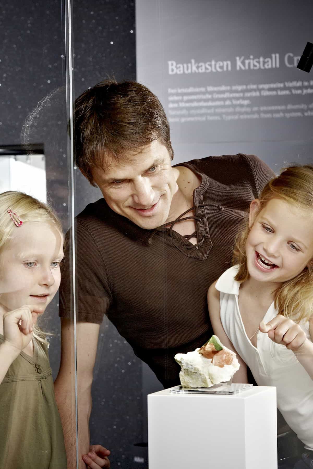 Kinder und Vater bestaunen Mineralien im Museum Bramberg – Ausstellung zu Kristallen und Edelsteinen im Nationalpark Hohe Tauern, familienfreundliche Sehenswürdigkeit in der Wildkogel-Arena.