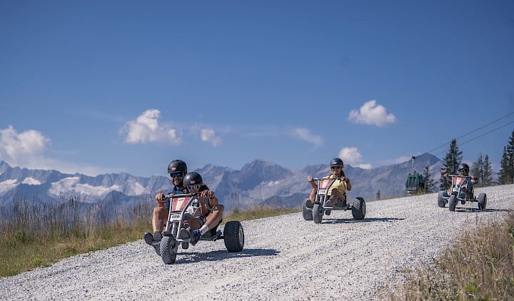 Family riding mountain carts down the 4 km long mountain cart track in the Wildkogel Arena – a thrilling outdoor activity for all ages with panoramic views of the peaks of the Hohe Tauern.